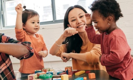 education, arts and community grants: Asian woman teaching and playing with two young children