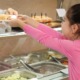 free school meals ending: young girl in pink shirt gets food from cafeteria worker