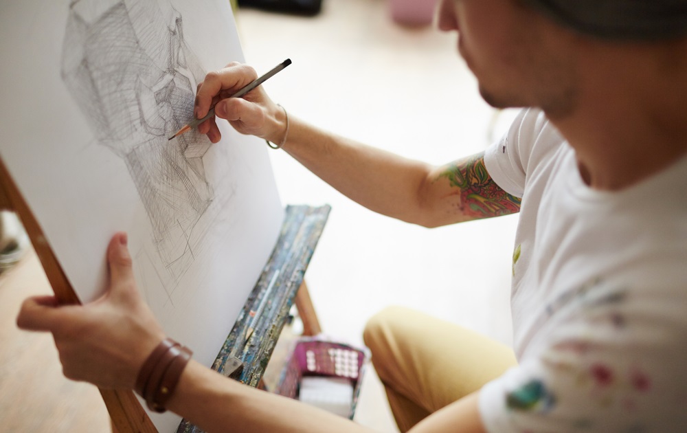 arts program grants, arts-based mental health, Big Thought: young man with tattoo on arm working on drawing