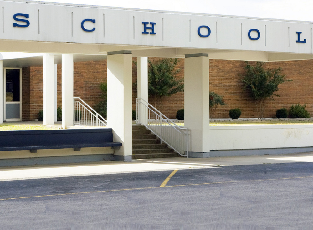 School violence: Red brick and white-pillared building entry steps with word "Dchool" in blue letters on white cement above steps