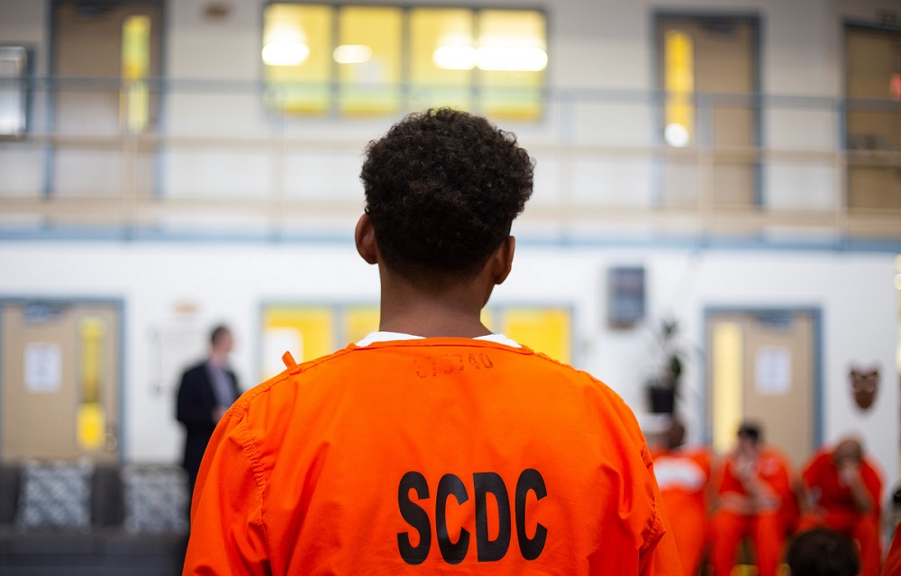 prisoners want more education in prison: young black prisoner in orange garb looking at something