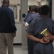 study says schooling for incarcerated youth is inferior: boy in juvenile detention holds book behind back as he walks in line with other detainees