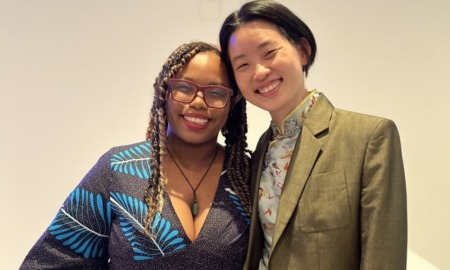 Asian-Black activism rekindled: A black woman and an Asian woman pose side by side, against a blank wall of a convention hall.