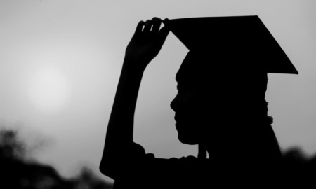 Working at school or nonprofit could erase student loans: silhouette of young woman with graduation cap on
