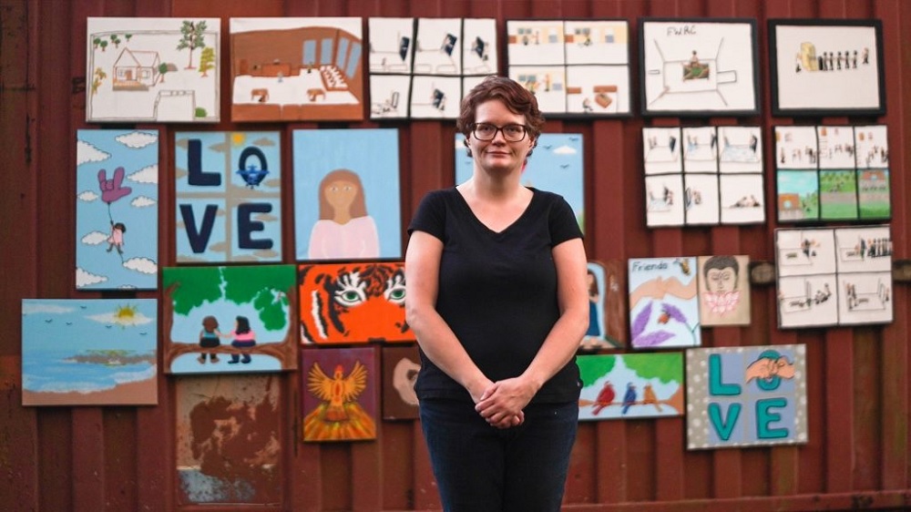 Being Michelle documentary: short-haired woman in black shirt stands in front of wall of art