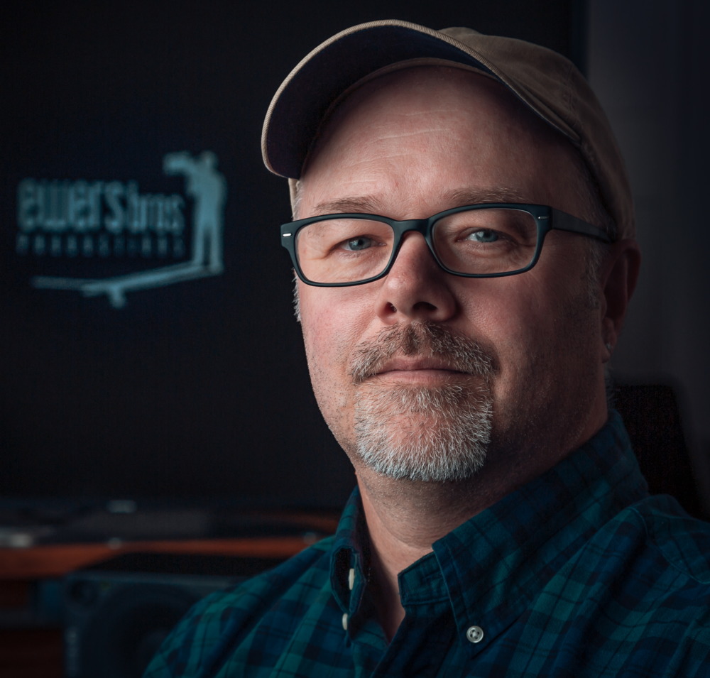 Mental Illness: Close-up of middle-aged man with short grey beard and black framed glasses wearing baseball cap and navy shirt