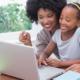 Disadvantaged girls' and women's education grants: Black mother and child smiling while on laptop together