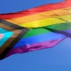 Wisconsin school board pride flag ban: progress pride flag waving in wind against blue sky