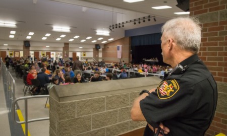 school police debate: school security guard looks out over cafeteria full of students