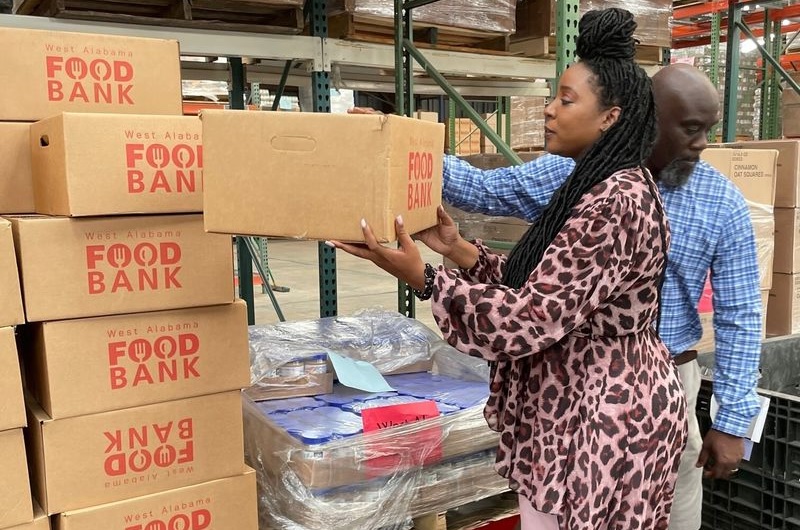 Alabama's food deserts: black woman with long hair and bald black man pack and stack food bank boxes