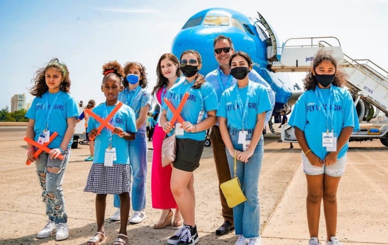 aviation education grants: group of girls in bright blue shirts standing in front of plane on tarmac