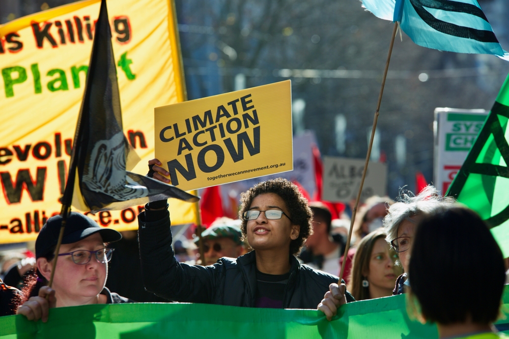 Climate change protest: Young people in street carrying protest signs about climate change
