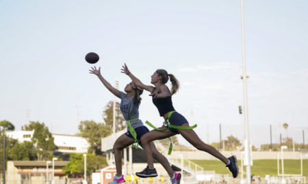 Girls' flag football: Two teen girls chasing football down playing field