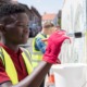 community project grants: black boy with gloves on paints an outdoor wall