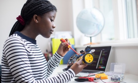 disadvantaged youth STEM grants: black girl with long hair works on robot car at desk