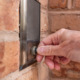 No warrant entry: Hand pressing culver doorbell set in red brick wall