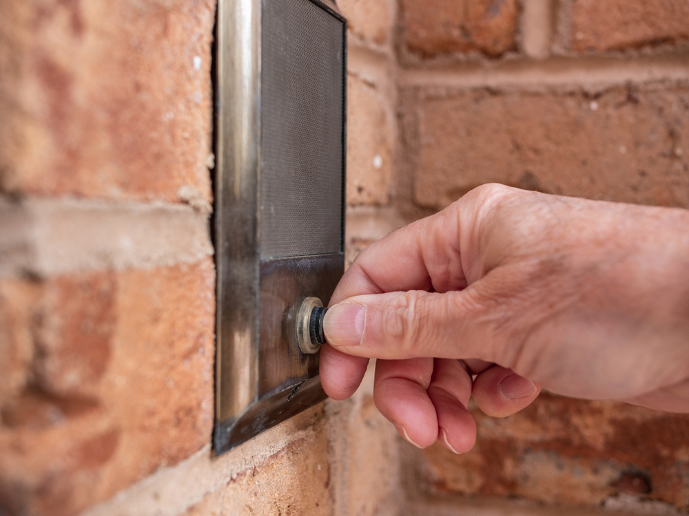 No warrant entry: Hand pressing silver doorbell set in red brick wall