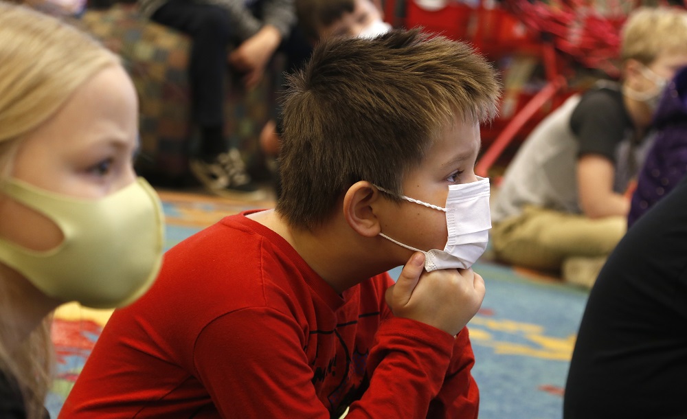 social emotional learning teaching: children on the floor with facemasks on listening to educator