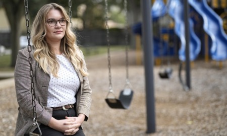 Schools struggle to staff up for youth mental health crisis: female teacher with long hair and glasses sitting on swingset swing