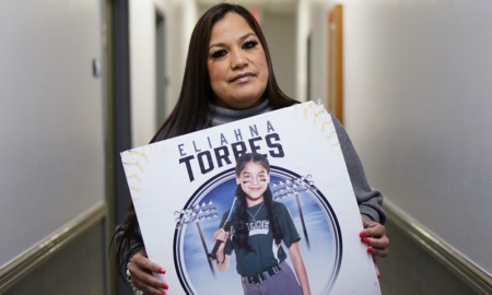 Uvalde mom sues police and gunmaker: Latina woman with long hair holding picture of girl in softball uniform posing