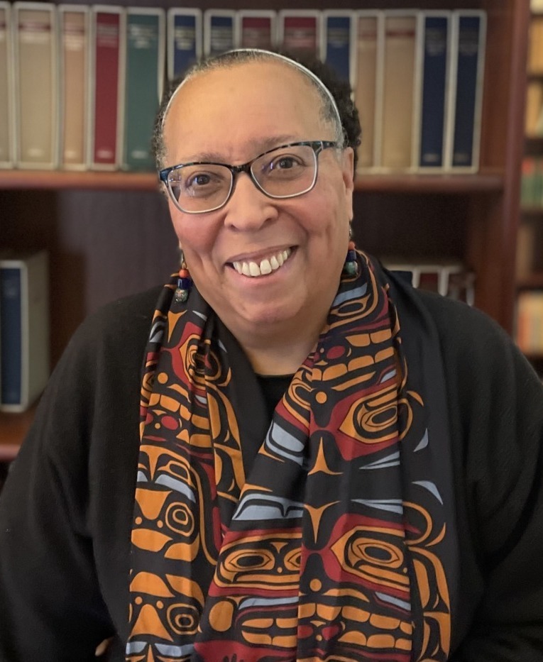 Karen Pittman opinion: Black woman with dark-frame glasses an hair pulled back wearing dark jacket and long, colorful scarf with bookshelf in the background.