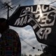 BLM sets up student relief fund as loan forgiveness stalls: man in shirt covered in flags holding a Black Lives Matter flag