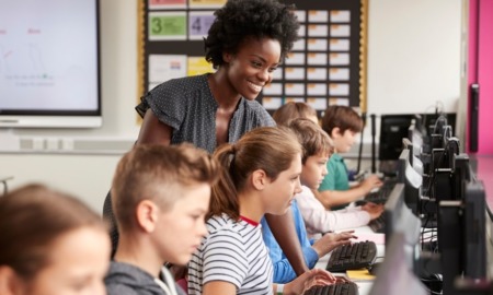 STEM education racial equity program grants: black female teacher helping students on computers