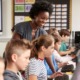 STEM education racial equity program grants: black female teacher helping students on computers