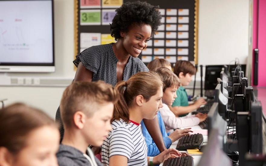 middle school education, racial equity, STEM education program grants: black female teacher helping students on computers