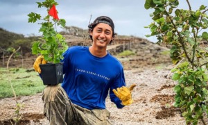 Hawaii Oregon youth, environment, community grants: young man in blue shirt holding plant and smiling