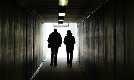 Sex Offender Registry: Silhouette of two people walking away in a dark tunnel toward a lighted exit