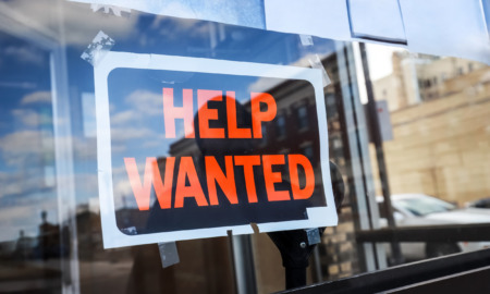 ODT Hiring: Black and orange Help Wanted sign in glass window