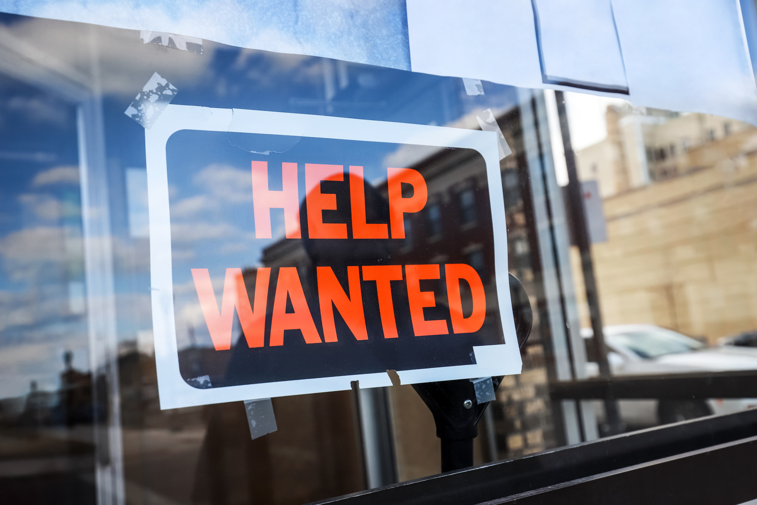 ODT Hiring: Black and orange Help Wanted sign in glass window