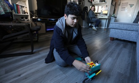 New York pilot dyslexia program: boy plays with legos on floor of home with parent in background