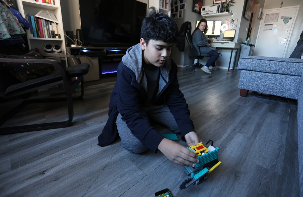 New York pilot dyslexia program: boy plays with legos on floor of home with parent in background
