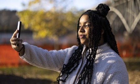 Students turn to TikTok to fill gaps in school lessons: black girl with long hair takes a selfie on phone outside