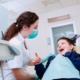tips for finding dental care for disabled youth: happy child looks up at female dentist in dentist's chair