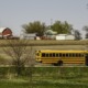 rural community and education grants: school bus drives down road with farm in background