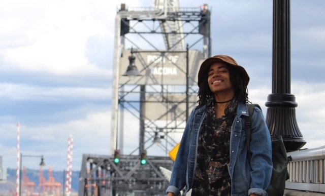 foster youth abortion access: image of happy young woman in hat in front of metal bridge 