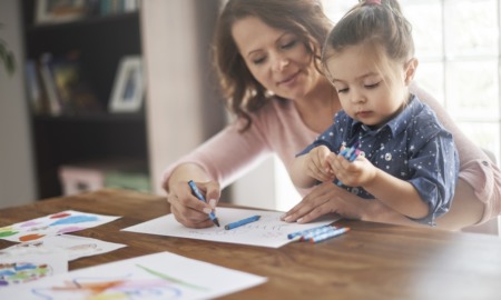 Home-based child care research, early childhood wellness and development grants: mother teaching child things with crayons and paper