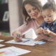 Home-based child care research, early childhood wellness and development grants: mother teaching child things with crayons and paper