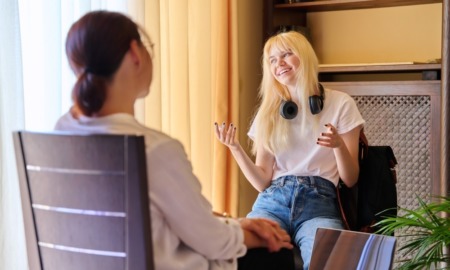 youth at risk of psychosis grants: happy teenage female with light hair and headphones around neck in therapy session