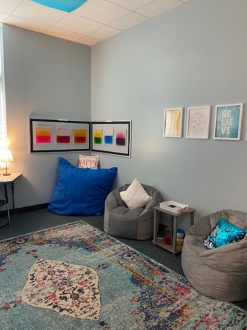 Zen Den calming rooms: Pale blie room with bean bag chairs, a blue oriental pattern rug and student art on the walls