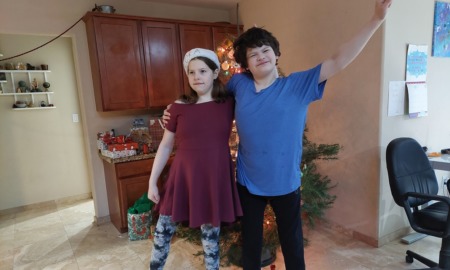 Nevada gave away $5 million to children with disabilities: two happy youth with disabilities side-hugging in front of Christmas tree