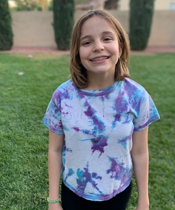 Nevada donated $5 million to children with disabilities: Smiling Caucasian girl with braces on her teeth in her backyard