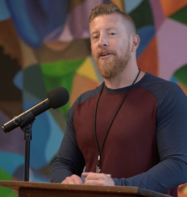 Tennessee ban on juvenile life sentences: White man with red hair and beard in dark, long-sleeved t-shirt stands behind podium speaking into microphone