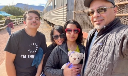 effects of pandemic school closure on students with disabilities: family stands next to train with daughter holding teddy bear