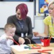 early education for children with disabilities: two teachers help a young child with down syndrome paint
