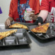 School lunches sugar: Closeup of three black sectioned lnnch trays with piece of pizza on each tray