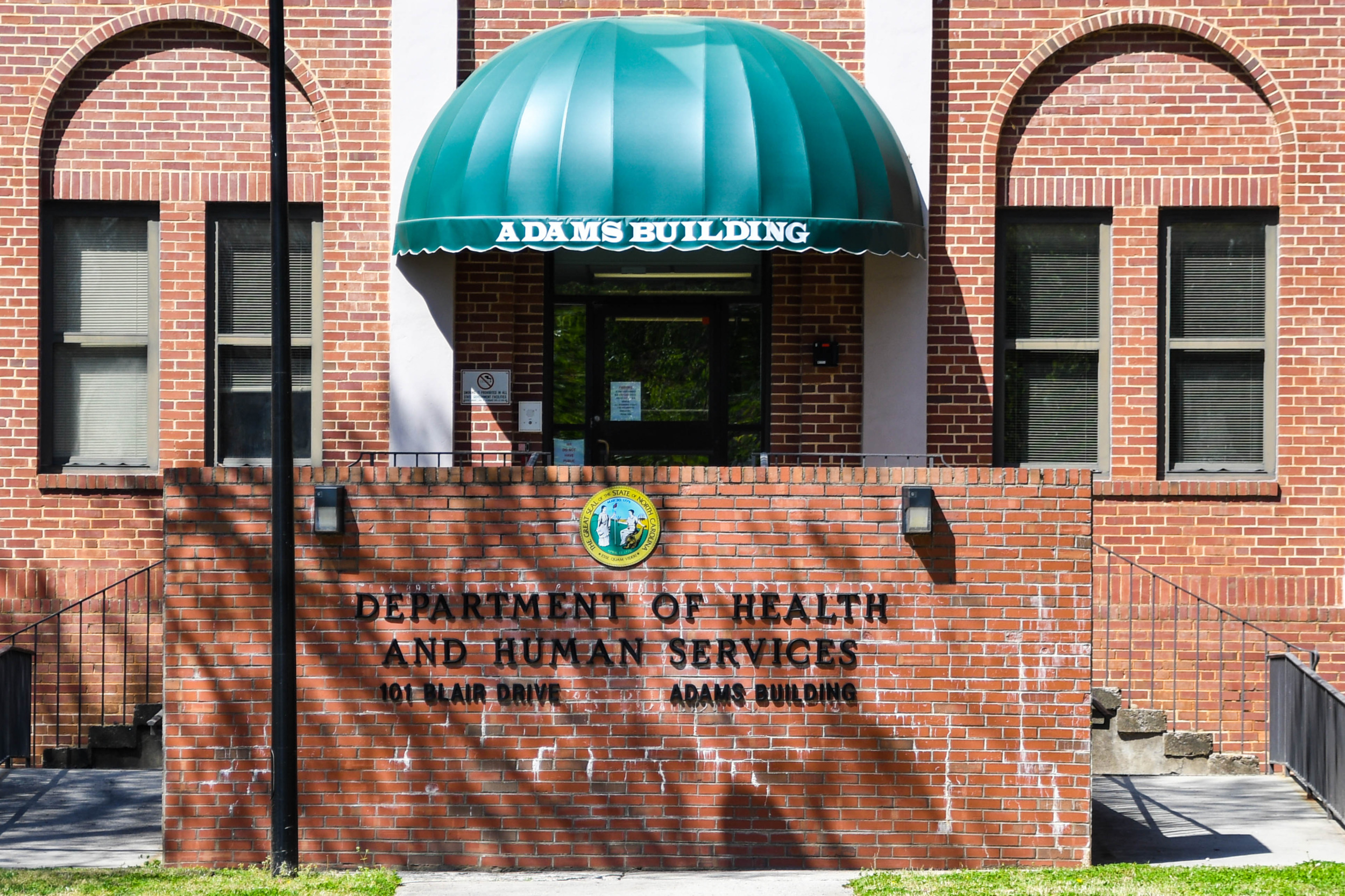 Foster care lawsuit: Red brick building with green entry stoop canopy and black letter signage "Department of Health and Human Services"